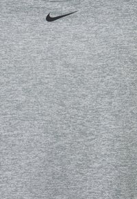 Gray short-sleeve T-shirt made of a textured fabric. Features a black Nike logo on the upper left.