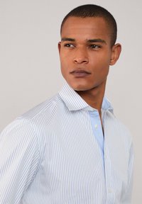 Blauw-wit gestreepte overhemd met een button-down kraag, gemaakt van textuurstof en met een contrasterende lichtblauwe binnenkraag.
