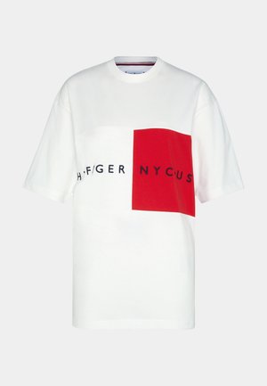 Biała koszulka z krótkim rękawem z czerwonym kwadratem na prawym przodzie i czarnym tekstem częściowo czytającym "HILFIGER NYC US" na wysokości klatki piersiowej.