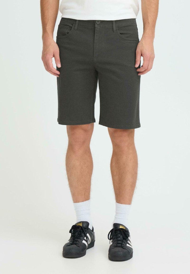 Shorts gris foncé en denim, dotés d'un design à cinq poches, de passants pour ceinture et d'une coupe droite, associés à des baskets noires et des chaussettes blanches.
