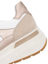 Close-up van de hiel van een beige en metallic gouden sneaker met een witte tussenzool en een bruine rubberen buitenzool, met zichtbare gestructureerde leer- en suède materialen.