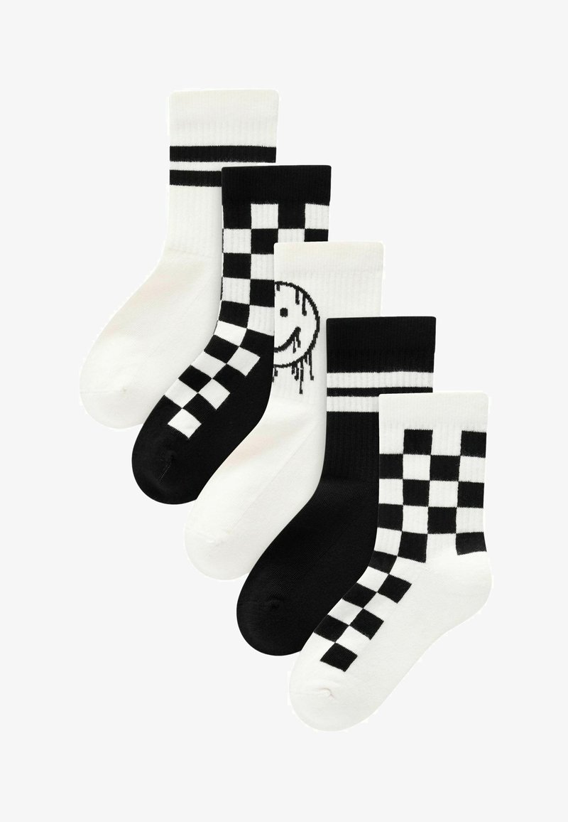 Cinq paires de chaussettes en noir et blanc. Les caractéristiques comprennent des rayures, des motifs à carreaux et un graphique de visage souriant sur une paire.