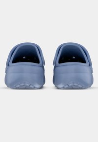 Kék gumi klumpák lekerekített hátsó résszel, texturált belső résszel, szellőző nyílásokkal az oldalakon és sima külső felülettel.