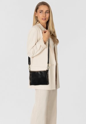 Borsa a tracolla in pelle nera con borchie dorate lungo i bordi, completata da una tracolla rimovibile. Texture liscia e forma rettangolare.