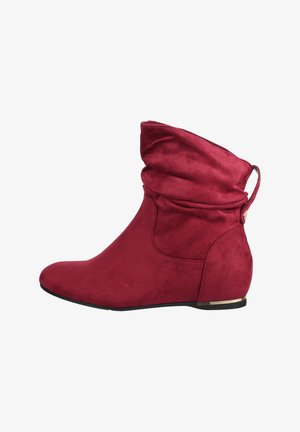 Rode suède enkellaars met een slouchy bovenzijde, ronde neus, lage wiggenhak en een klein metallic detail op de zool bij de hak.