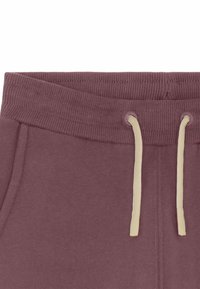 Des sweatpants bordeaux foncé avec une taille côtelée, des cordons de serrage crème et des poches latérales. Tissu doux avec une texture lisse.
