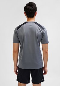 Gray athletic shirt featuring short sleeves, round neck, and black accents on the shoulders. Material appears lightweight and smooth.