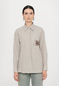 Striped, button-up shirt in light beige and brown, featuring a chest pocket with a brown logo. Long sleeves with buttoned cuffs.