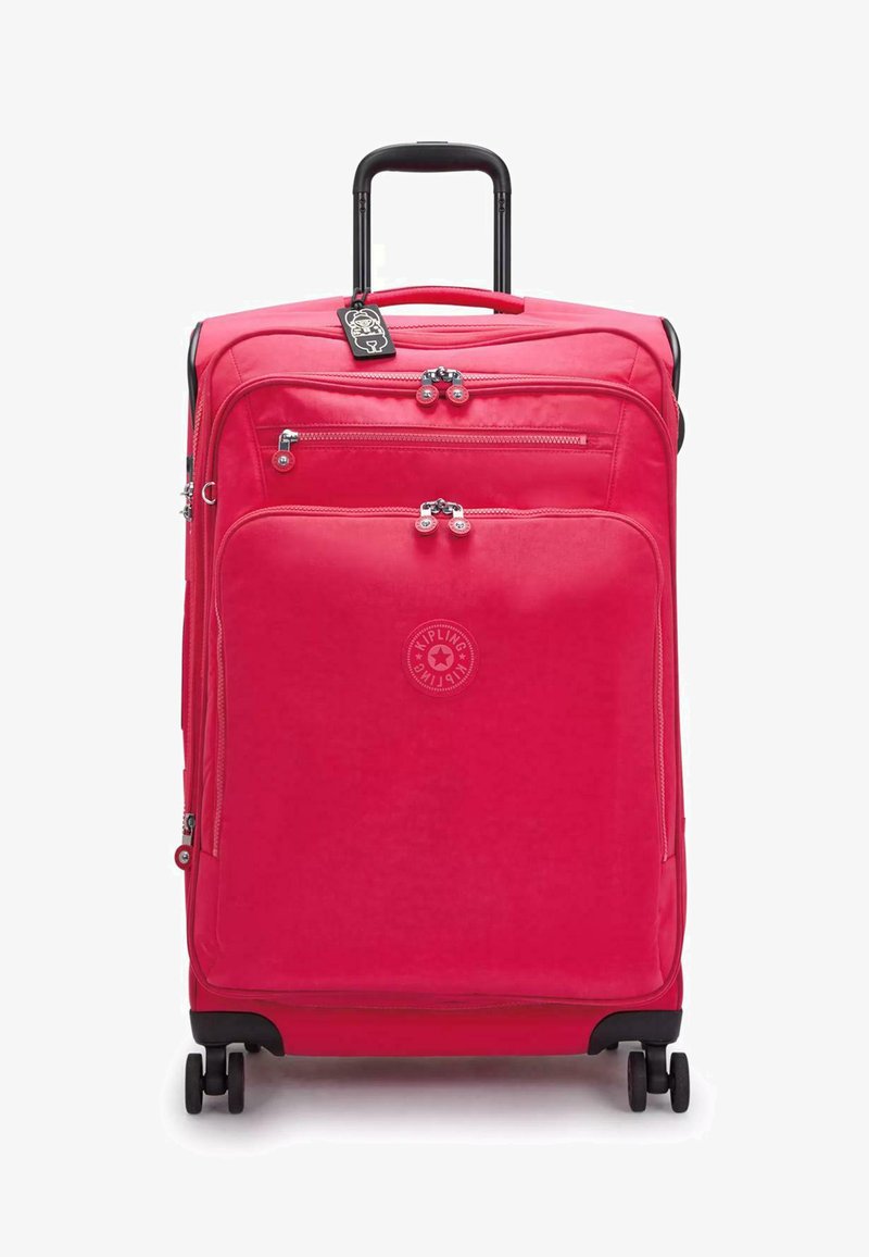 Růžový cestovní kufr s více zipovými přihrádkami, texturovaná tkanina, logo vpředu a černá teleskopická rukojeť a kolečka.