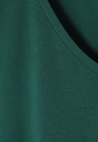 Top verde senza maniche realizzato in tessuto morbido, con scollatura rotonda e una sottile texture, dalla vestibilità aderente e privo di ulteriori dettagli.