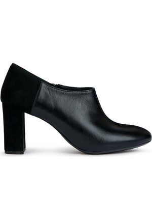 Zwarte hoge hak schoen met een gladleren bovenwerk en een suede achterkant. Het ontwerp heeft een ronde neus en een chunky vierkante hak.