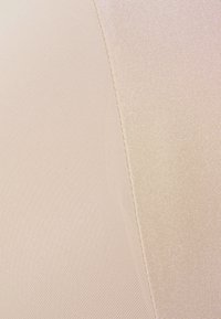 Hudfarget stoff med en jevn tekstur, med lyse beige nyanser og en subtil glans, som viser intrikate vevde mønstre og broderte kanter.
