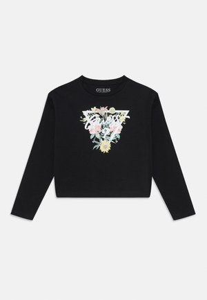 Svart langermet crop top med et fargerikt blomsterdesign i trekantform, hvor merkevaren "Guess" er tydelig vist.