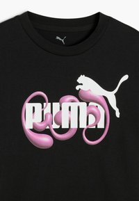 Melns T-krekls ar balto "PUMA" logo, kurā iekļautas rozā, plūstošas formas, un virs teksta redzama balta puma silueta, kas lēkā.