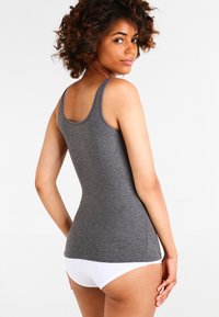 Gray fitted tank top with thin straps, made of soft fabric. Features a rounded neckline and a smooth texture. Worn with white underwear.