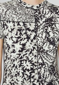 Koszulka z krótkim rękawem z kontrastowym czarno-białym wzorem kwiatowym o teksturowanym wykończeniu oraz okrągłym dekoltem.