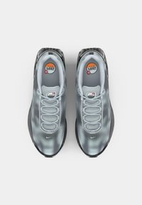 Tenisici Nike Air Max z zgornjim delom iz sive mreže z vzorcem pik, oblazinjenim ovratnikom, elastičnimi vezalkami in črnim gumijastim podplatom.