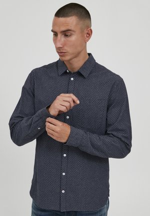 Cămașă albastră cu nasturi, cu modele micuțe albe, guler cu rever, mâneci lungi și manșete cu nasturi, fabricată dintr-un material ușor.