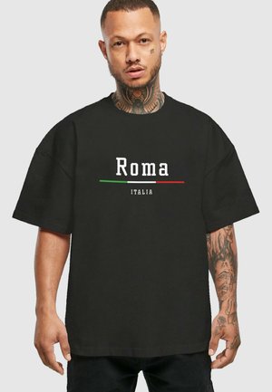 Black t-shirt featuring “Roma” in white text, with “ITALIA” below. The design includes green and red accent lines. Relaxed fit and short sleeves.