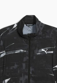 Veste noire avec des motifs abstraits gris et un col haut. Présente un logo Puma blanc à l'avant près de la fermeture éclair.