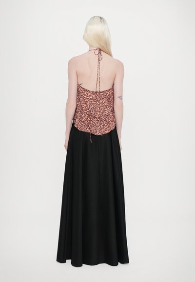 Haut halter fleuri marron avec une coupe décontractée, associé à une robe longue noir fluide, créant un design bicolore contrasté.