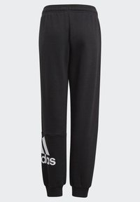 Mustat verkkarit, rento istuvuus, joustava vyötärönauha, resorit nilkoissa ja valkoinen Adidas-logo vasemmassa lahkeessa. Pehmeä kangas.