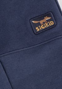 Marineblaue Baumwollstoffe verfügen über eine genähte Tasche mit einem rechteckigen Patch, der eine Fuchs-Grafik und "sigikid" in gelber Schrift zeigt.