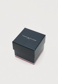 Tommy Hilfiger watch box, square shape, dark blue exterior, white and red accents at the base, logo printed on top.