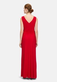 Rotes ärmelloses Maxikleid mit V-Ausschnitt, mit einem eng anliegenden Oberteil und sanften Raffungselementen an der Taille, gefertigt aus einem glatten, elastischen Stoff.