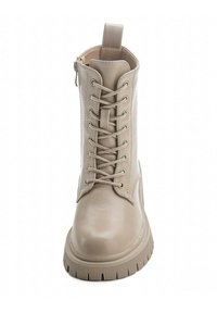 Stivaletto in pelle beige con lacci frontali, zip laterale e suola in gomma texturizzata. Presenta un pratico pull tab sul retro per indossarlo facilmente.
