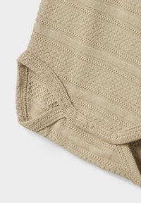 Beige knitted baby bodysuit featuring textured stripes, a cotton blend, and snap fasteners at the bottom for easy dressing.