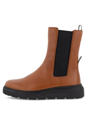 Bottine en cuir marron à la cheville avec semelle noire épaisse, panneaux latéraux noirs élastiques et languettes à l’avant et à l’arrière.
