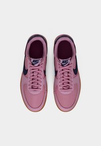 Adidași Nike în roz deschis cu accente bleumarin. Partea superioară este sintetică și netedă, cu vârf rotunjit și talpă plată de cauciuc. Prezintă șireturi clasice și branding.