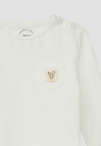 Witte langemouwen shirt met schouderdrukknoopjes, met een kleine beige zakpatch die een hartontwerp in een kleurrijk patroon toont.