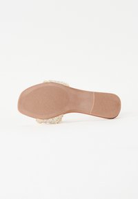 Semelle en caoutchouc beige avec une texture lisse, dotée d'un matériau supérieur duveteux de couleur crème. Conception plate avec une forme arrondie.