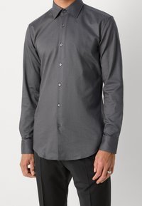 Donkergrijs, lang mouwen, overhemd met knopen, gemaakt van gladde stof, met een klassieke kraag en contrasterende knopen, gecombineerd met een zwarte broek.