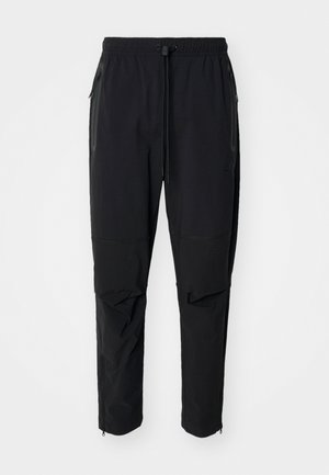 Schwarze, leichte outdoor Hosen mit elastischem Bund und verstellbarem Zugschnur. Ausgestattet mit Reißverschlusstaschen und tapered Bündchen.