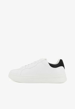 Baskets blanches avec une tige en cuir lisse, bout arrondi et design à lacets. Accents noirs sur le talon ; semelle texturée pour une meilleure adhérence. Logo de la marque sur le côté.