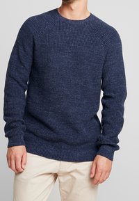 Mörkblå stickad tröja med ribbad textur, rundad hals, och långa ärmar, med en avslappnad passform och sänkt axeldesign.