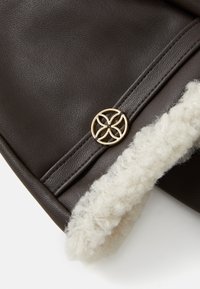 Accesoriu din piele maro închis, cu o margine din blană și un detaliu circular din hardware aurit cu un design floral.