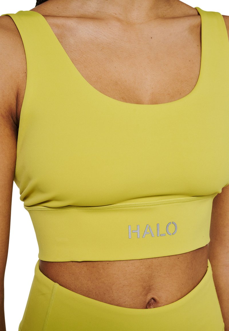Limegrøn sportsbh med en bred, rund halsudskæring, ribbet kant og "HALO" logo i sølv i midten. Lavet af blødt, strækbart materiale.