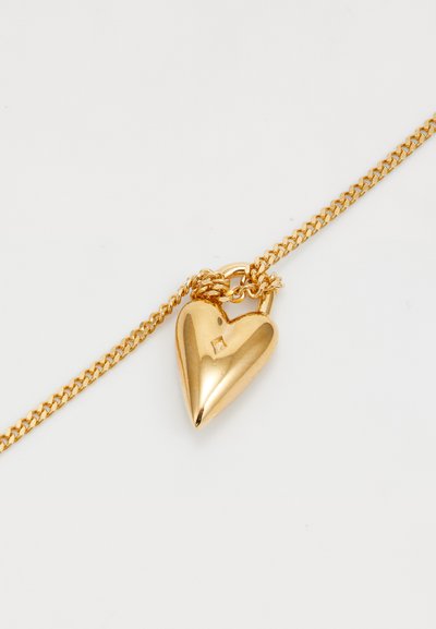 Guldhalsband med ett hjärtformat hänge i guld, med en vriden design och en liten fyrkantig accent på framsidan. Slät, reflekterande yta.