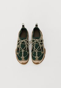 Green and tan athletic shoes with textured overlays, mesh accents, and reflective laces. Features pull tabs on the heel for easy wear.