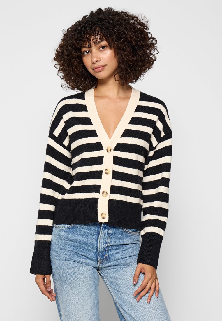 Gestreifter Cardigan in Schwarz und Creme, mit V-Ausschnitt, langen Ärmeln und fünf großen Knöpfen auf der Vorderseite. Strukturmaterial gestrickt.