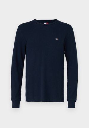 Mørkeblå langærmet skjorte i struktureret strikstof med rund halsudskæring og ribbede manchetter, med et lille logo på brystet.