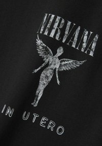 Sort T-shirt med et falmet hvidt grafik af en bevinget figur, med teksten "NIRVANA" ovenfor og "IN UTERO" nedenfor. 100% bomulds materiale.