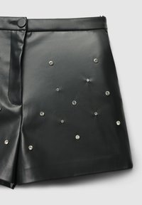 Gonna di pelle nera con borchie argentate disposte in un motivo sparso. Tessuto liscio con un design aderente e chiusura a bottoni.