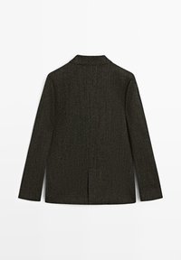 Ciemnozielona marynarka o fakturze z wzorem w jodełkę, z pojedynczym rozcięciem z tyłu i klapami; materiał wydaje się szorstki i tkany.