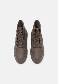 Pantofi din piele maro, de tip mid-top, cu vârfuri rotunjite, panouri texturate și tălpi ușoare din cauciuc. Au șireturi și căptușeală izolată.