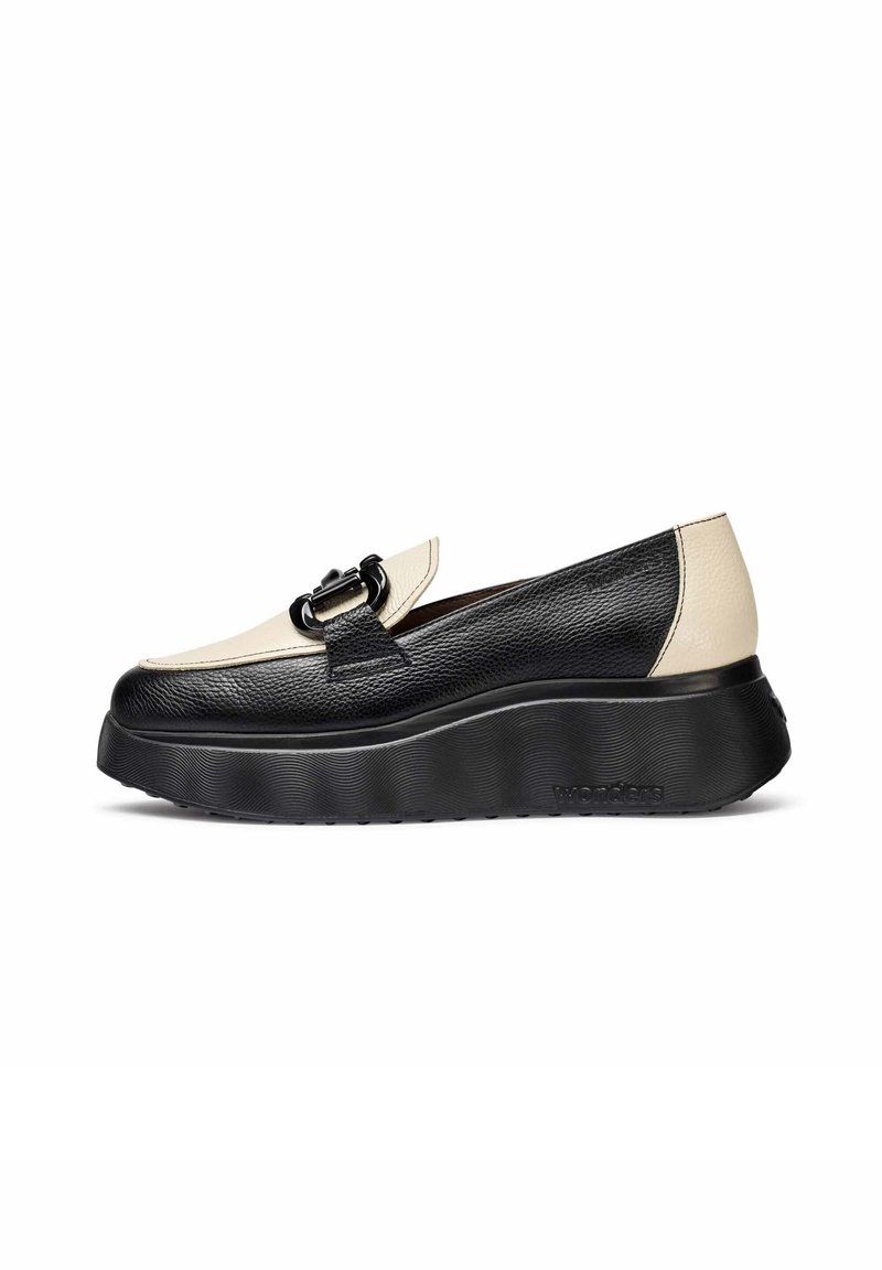 Mocassins en cuir noir et beige avec une épaisse semelle noire ondulée et un détail de boucle noire sur le dessus.